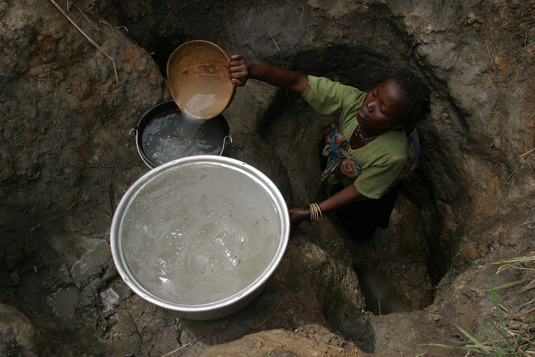 Eine Frau schöpft Wasser aus einem Wasserloch in der Demokratischen Republik Congo. | Bild: Unicef/Pierre Hotz